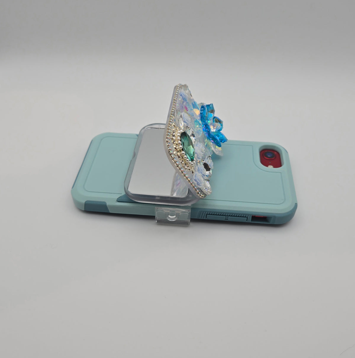 Blue floral phone mirror clip attached to a blue phone case, side view