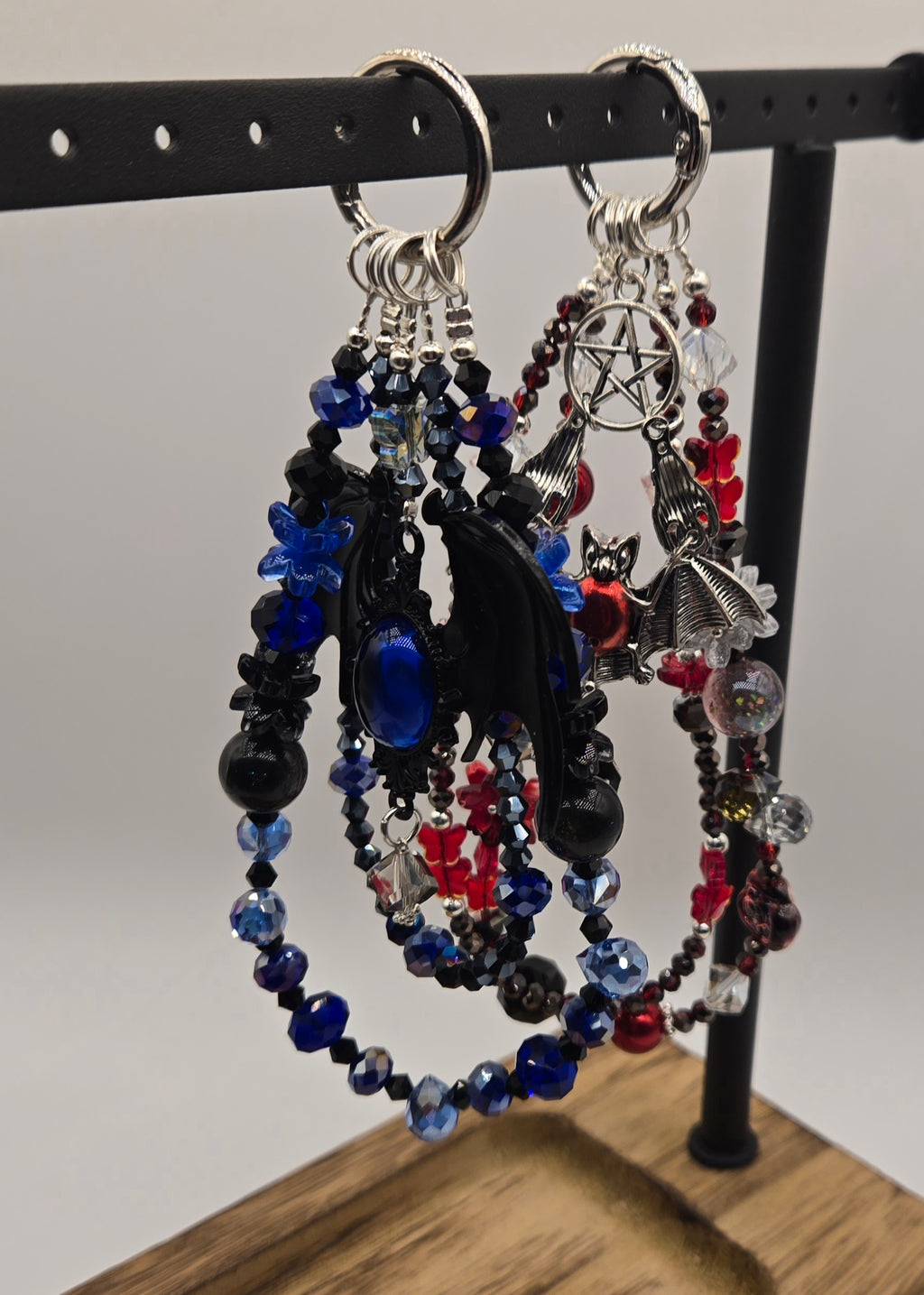 Black, blue and red Midnight Bat phone charms displayed together on a black jewelry stand