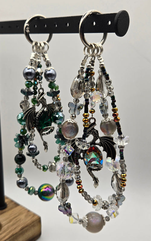 Assorted Dragon Magic phone charms hanging together in green, black, silver and crystal colorways