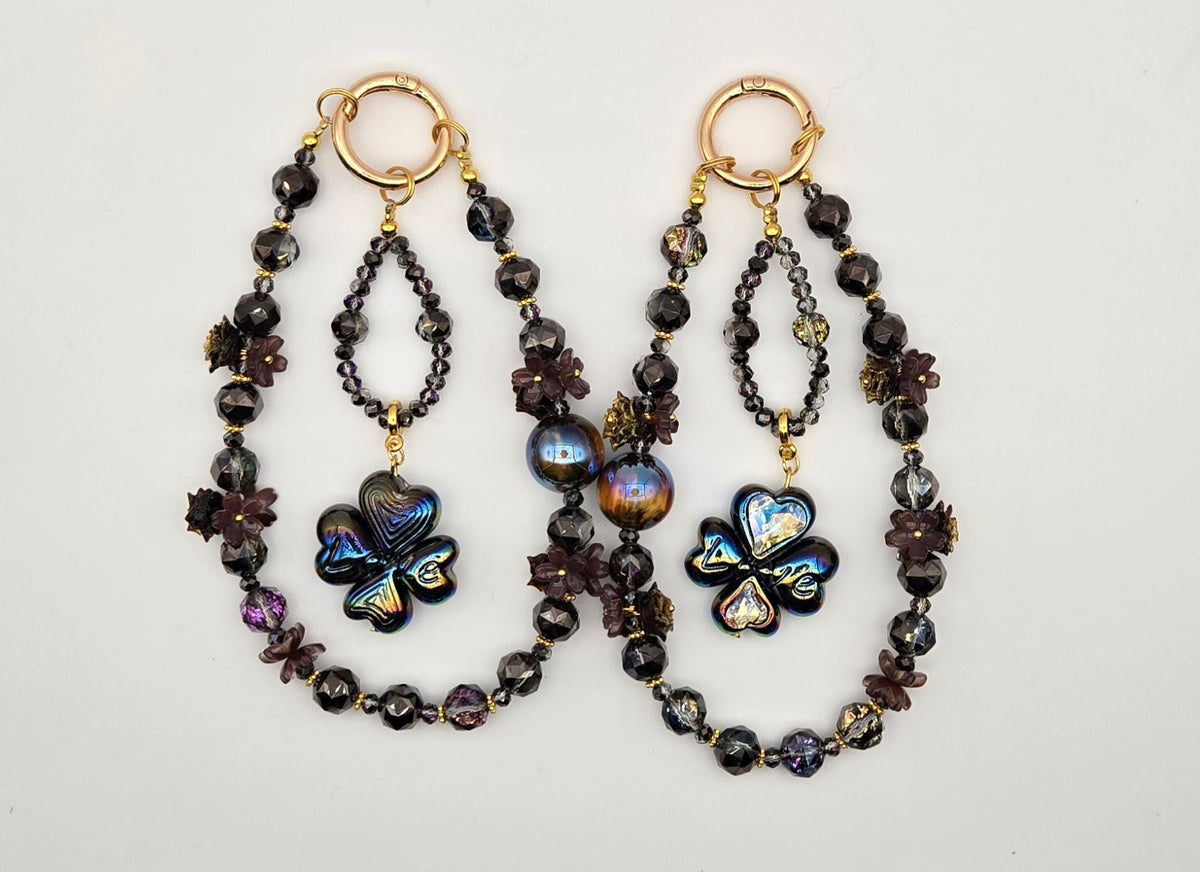 Midnight Clover phone charms with black beads, gold-tone hardware, dark floral accents and iridescent clover focal