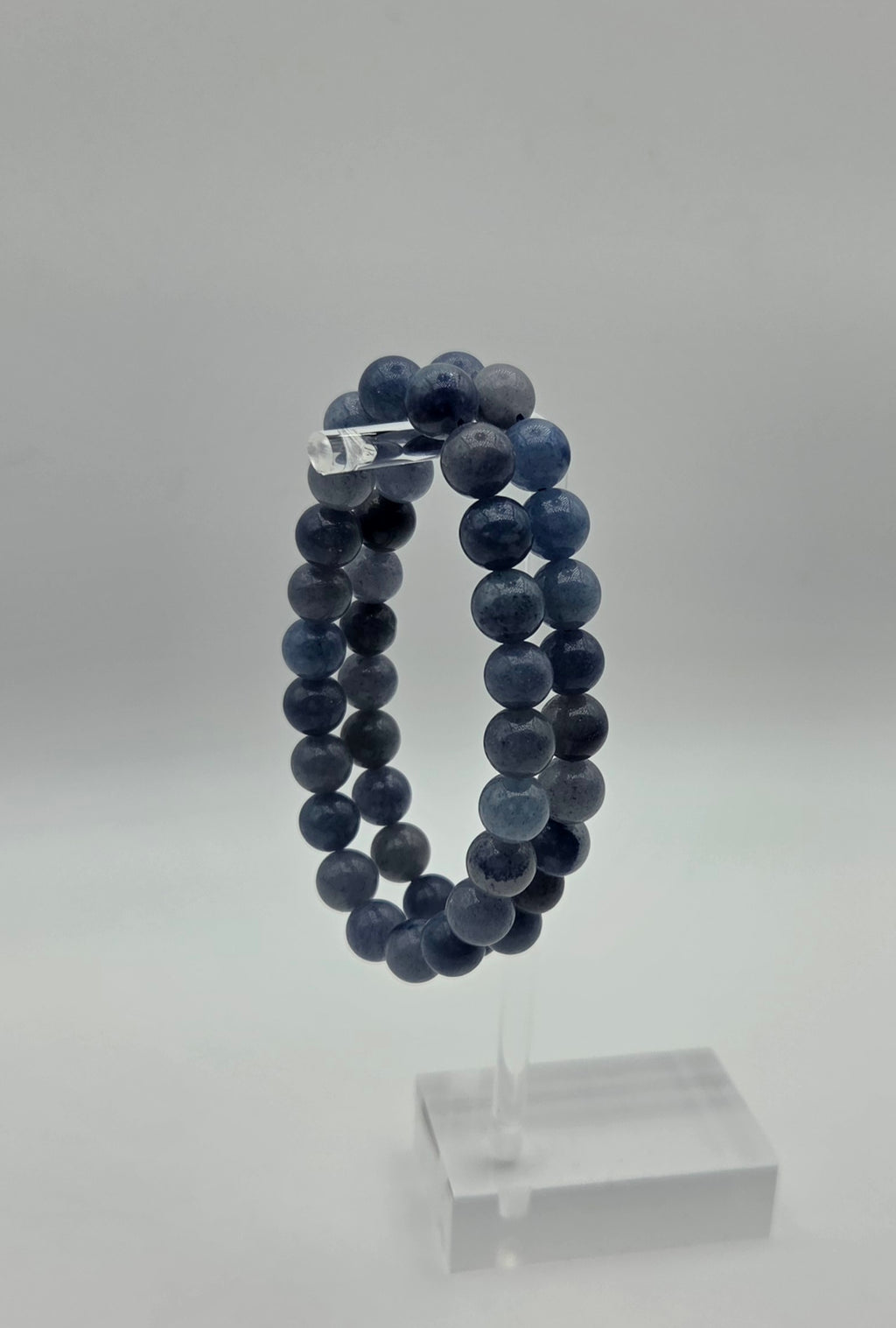 Blue aventurine beaded bracelet displayed on a clear acrylic jewelry stand