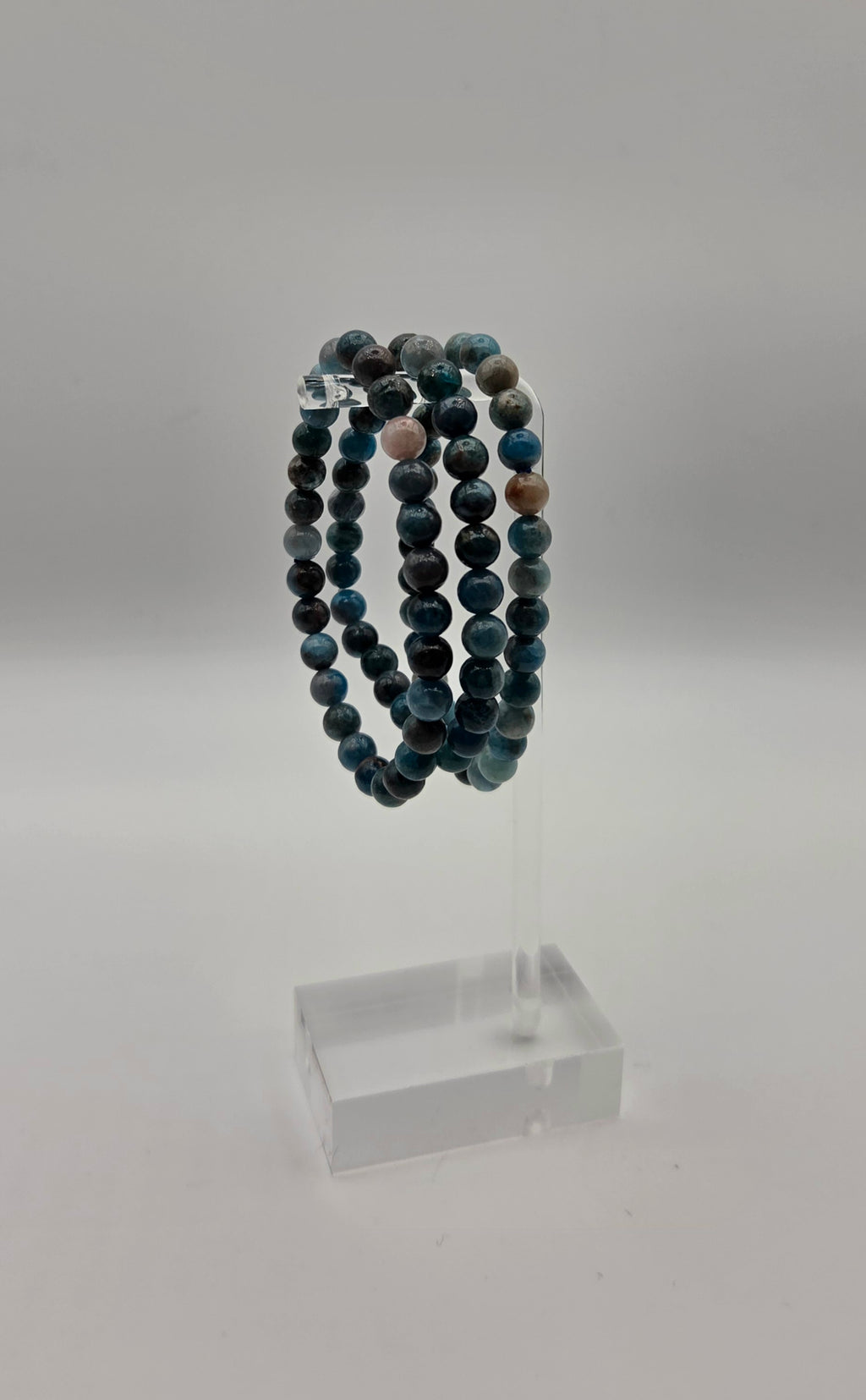 Blue apatite beaded stretch bracelets displayed on a clear acrylic jewelry stand