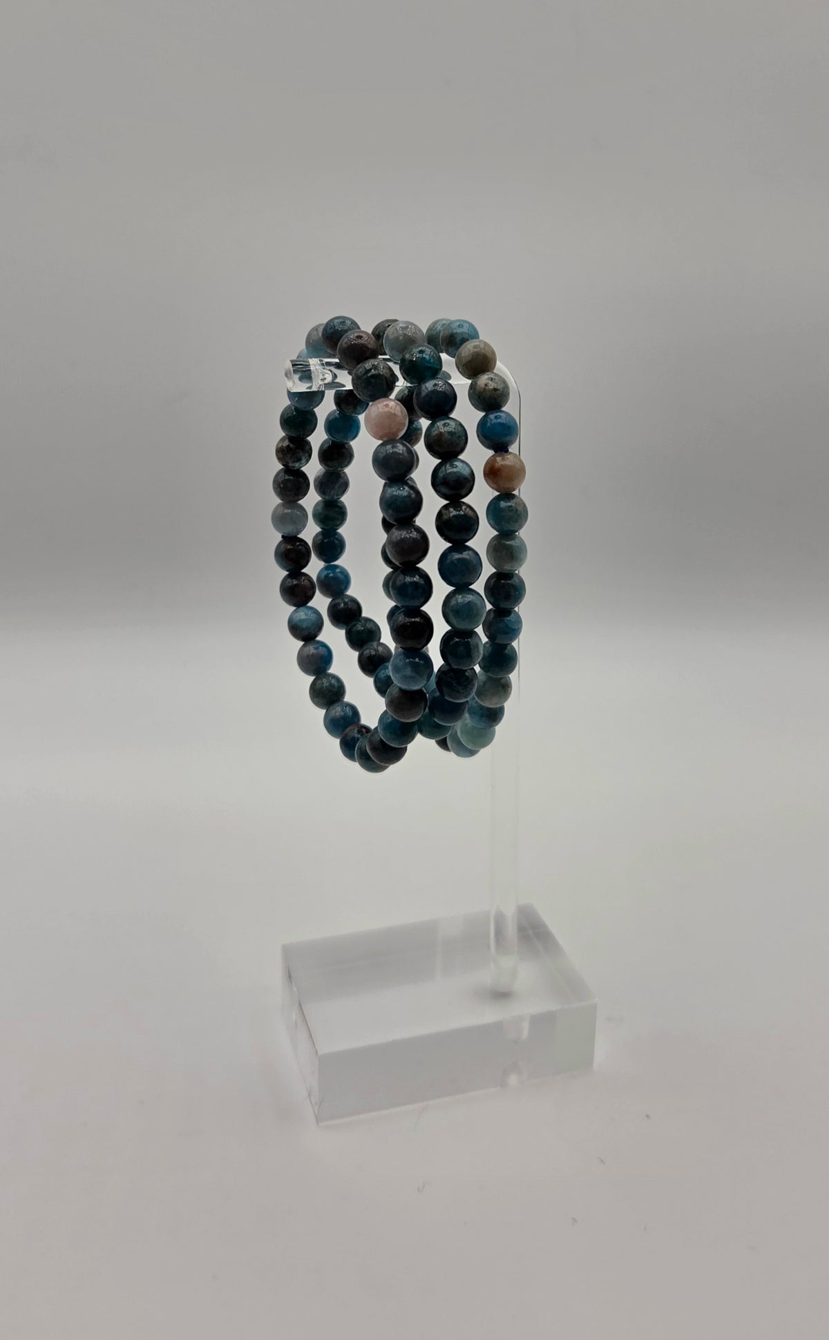 Blue apatite beaded stretch bracelets displayed on a clear acrylic jewelry stand