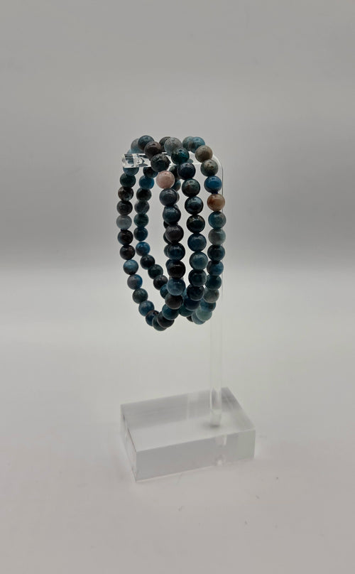 Blue apatite beaded stretch bracelets displayed on a clear acrylic jewelry stand