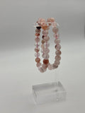 Acrylic stand: Fire quartz beaded stretch bracelets featuring blush pink peach and reddish brown stone beads on a clear acrylic stand